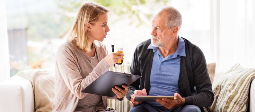 caregiver giving medicine to senior man