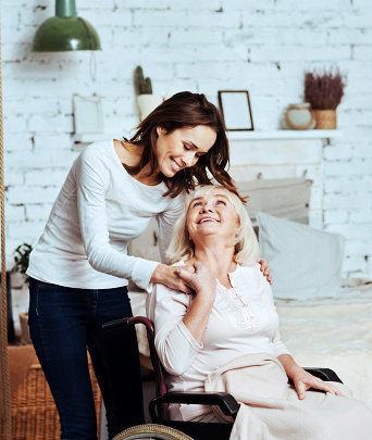 senior woman on a wheelchair smiling with her caregiver